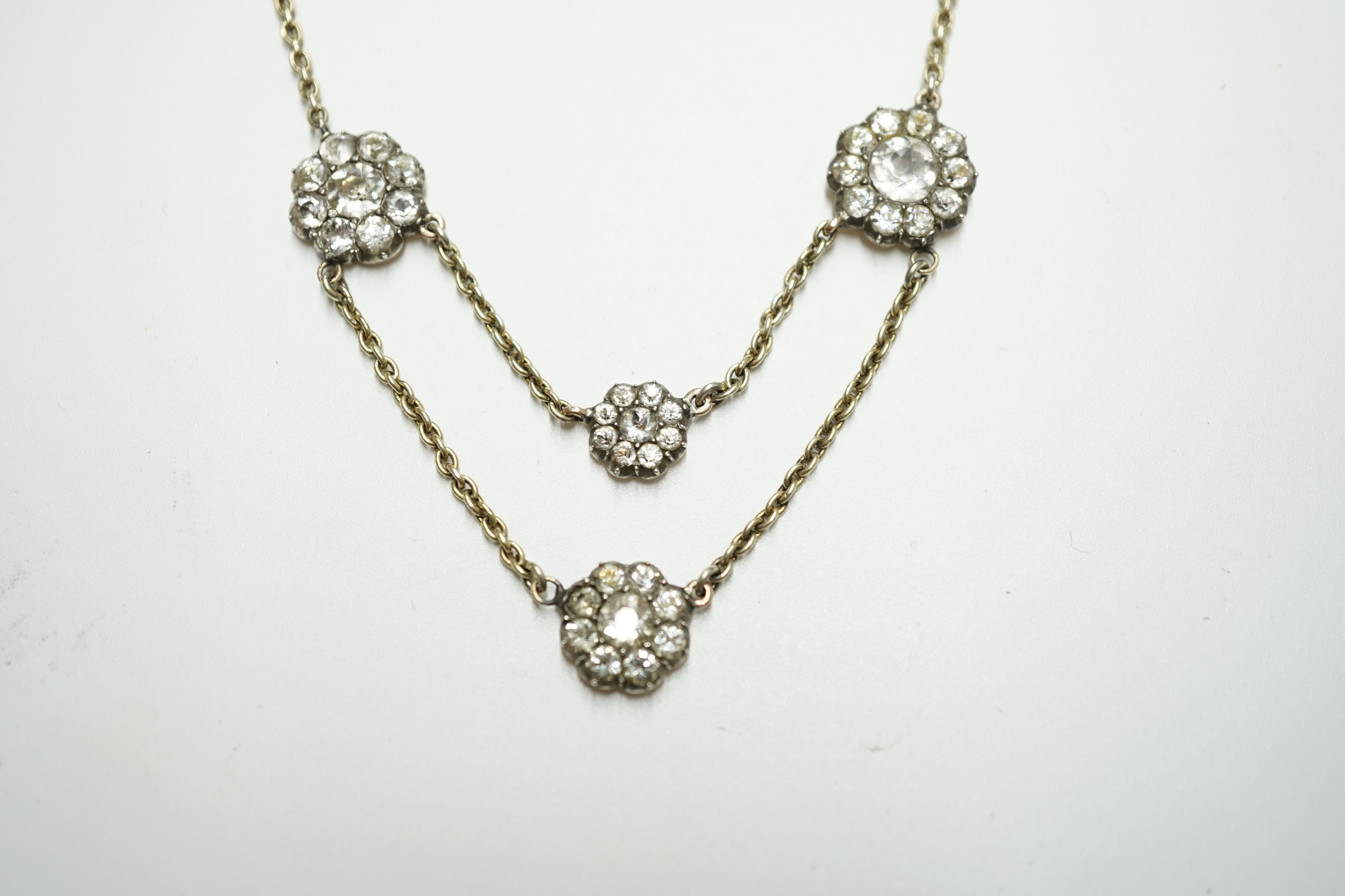 An early 20th century yellow metal and paste set multi flower head necklace, 39cm, gross weight 10.7 grams. Condition - poor to fair